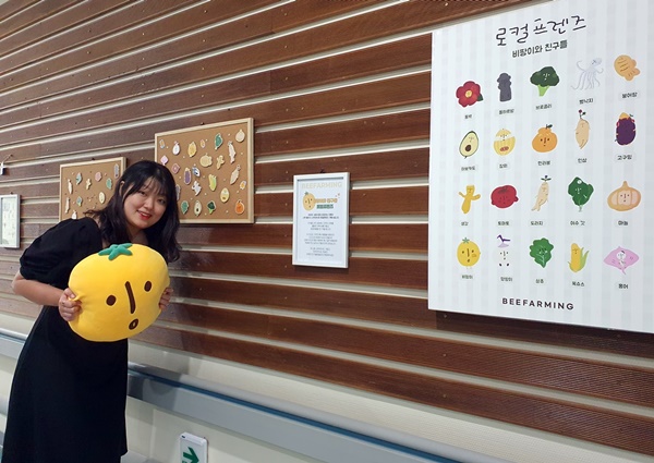 ▲ 화순전남대병원 소아청소년과 외래 갤러리 앞에서 ‘비파밍’ 김경희 대표가 비팡이 캐릭터 인형을 들고 사진 촬영하고 있다.