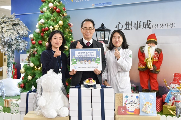 ▲ 한국백혈병소아암협회 김봉학 광주전남지회 사무국장(가운데)이 12월 23일 병원 1층 로비에서 소아 환아와 가족들을 위해 떡 케이크 등의 성탄 선물을 전달하고 있다.
