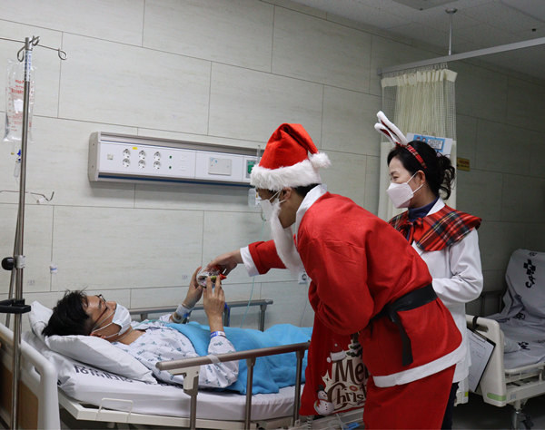▲ 산타로 변신한 도영우 환자경험평가위원장이 병동을 다니며 환자에게 선물을 나눠주고 있다. 